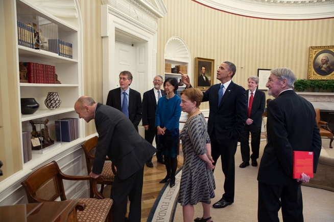 President Barack Obama points out several patent models while meeting with the 2013 American Nobel Laureates and their spouses in the Oval Office, Nov. 19, 2013. 